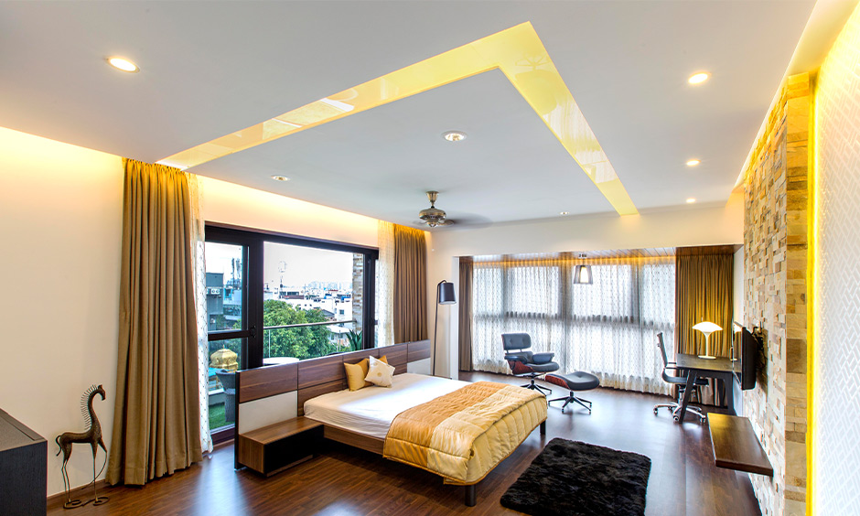 Bedroom with a latest down ceiling, recessed lights, and defined spaces for reading and relaxation.