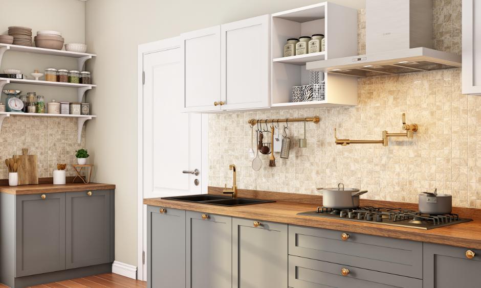 Teak wood shelves displaying brass masala boxes and clay pots in open kitchen.