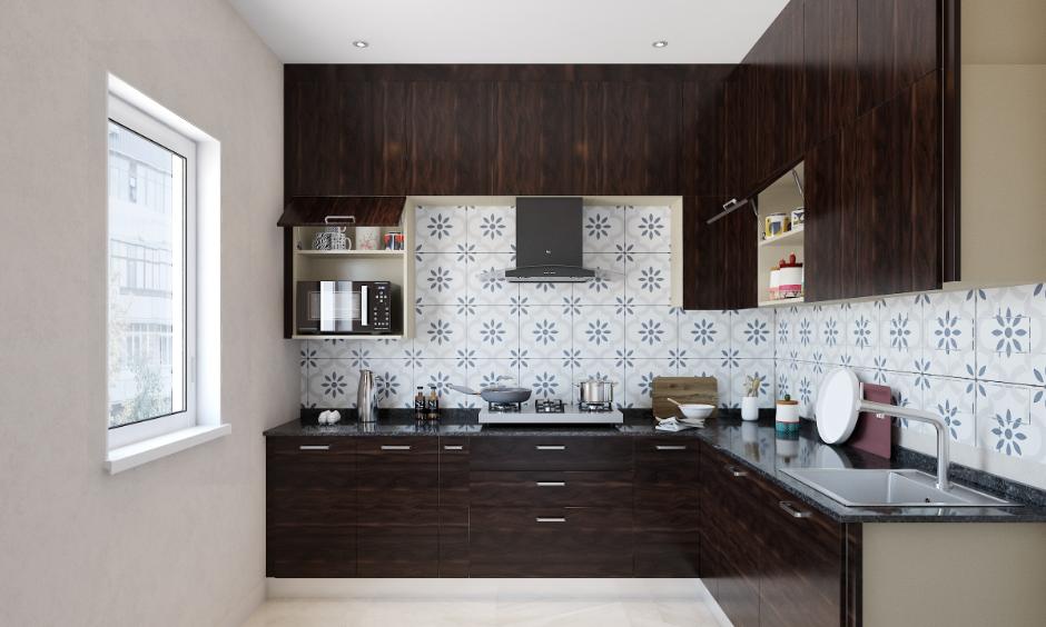Normal Indian kitchen design with dark wood cabinets, floral tile backsplash, chimney and microwave unit