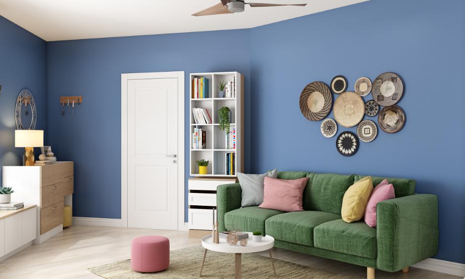 Living room with bold blue acrylic colour for wall painting, styled with a green sofa and wall decor