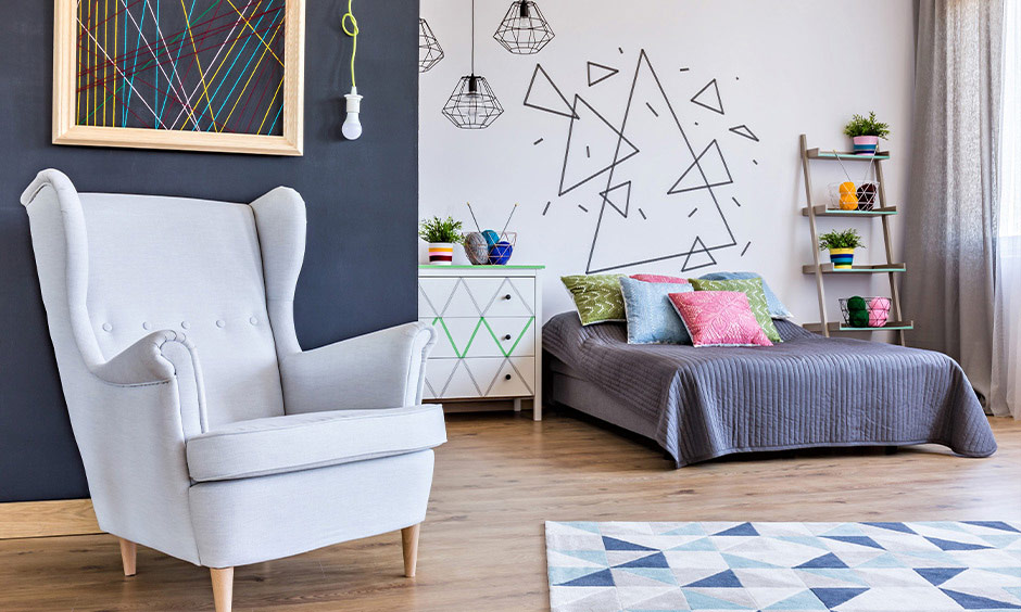 Trendy bedroom with an abstract mural of taped triangles creating an artistic edge on the back wall.