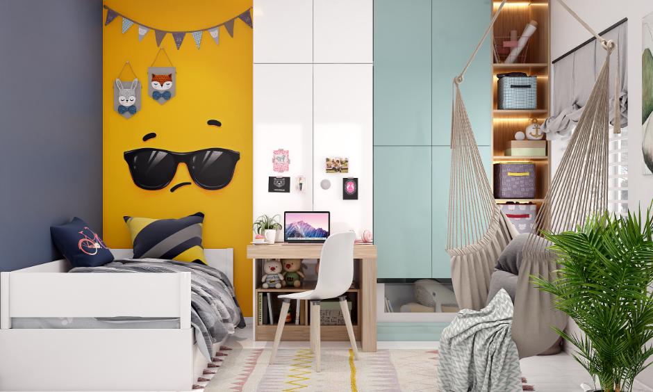 Kids' bedroom design with a study table, hammock chair, and bright yellow accent wall.