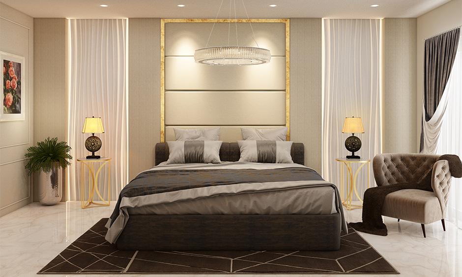 Beige monochromatic bedroom interior with golden lighting, soft white walls, and dark grey‑brown accents.