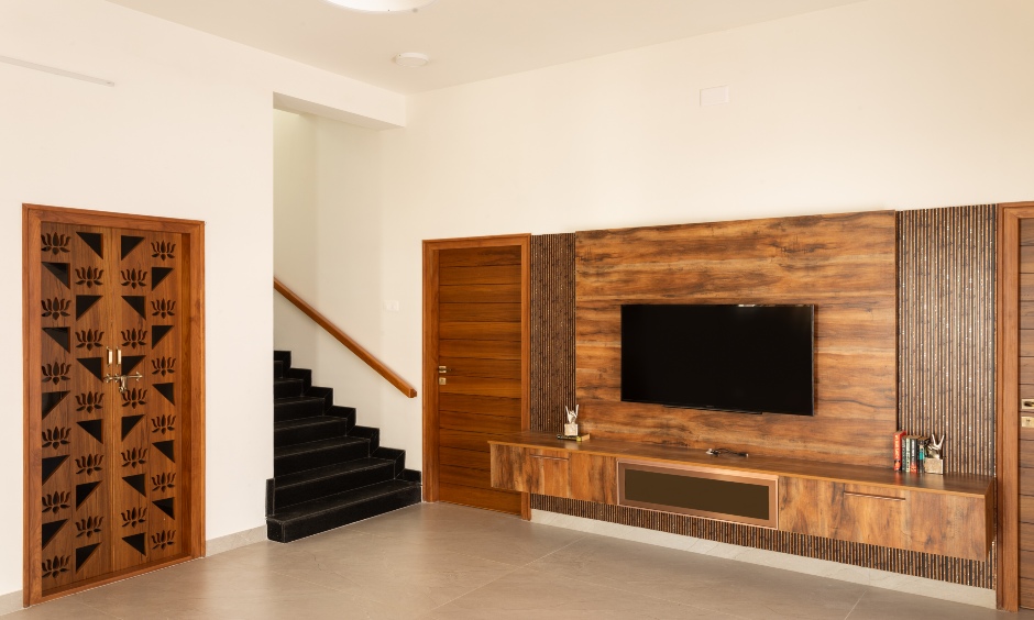 Daisy Avenue 2 BHK living room with wood-finished TV wall and subtle fluted detailing, Vishweshwara Nagar, Coimbatore.