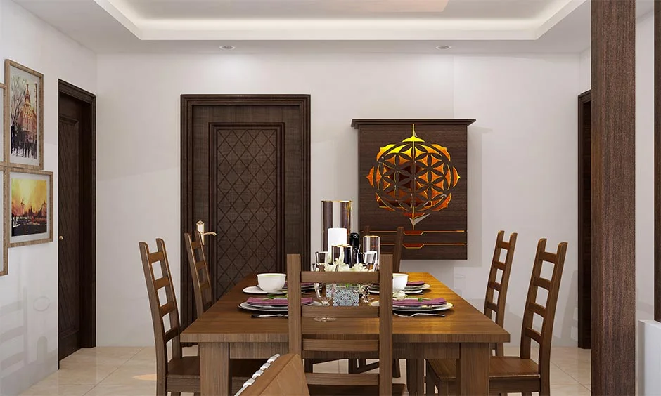 A wall-mounted dark wooden pooja mandir with a backlit mandala cut-out sits in a dining room.