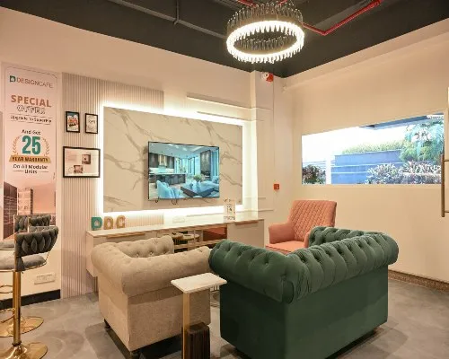 Luxury living room setup at DesignCafe Greater Noida featuring a tufted green sofa, and marble TV wall panel.