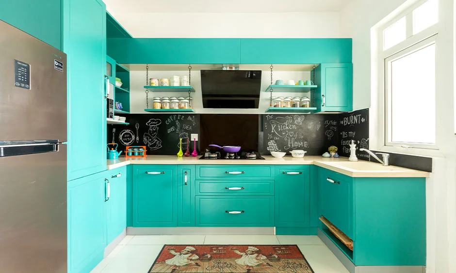 A compact teal kitchen uses overhead cupboards and integrated storage around the worktop