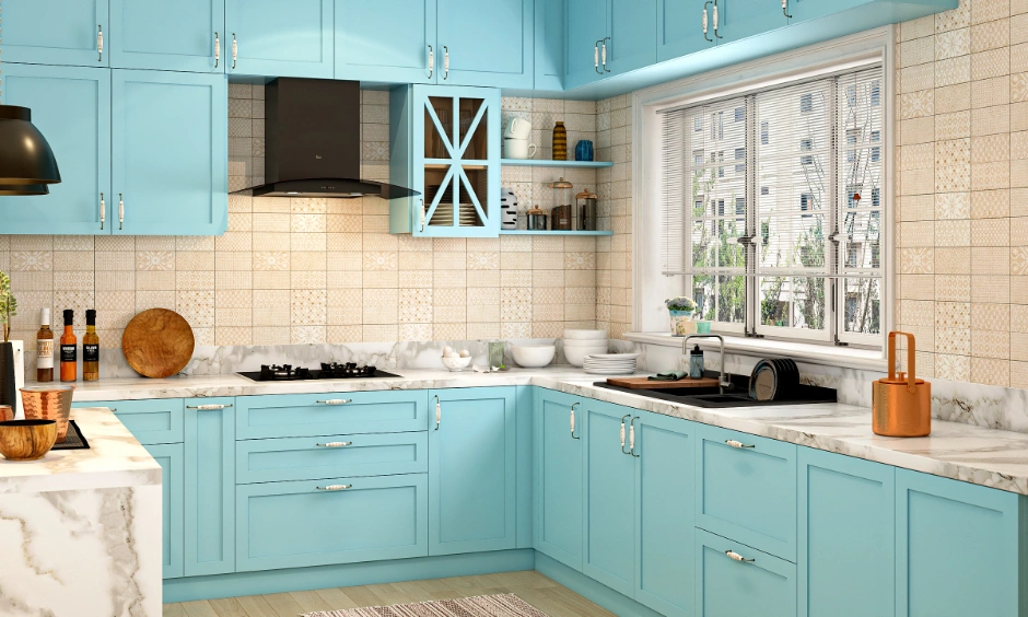 Classic L-shaped pastel blue modular kitchen with panelled shutters and marble countertop for a 3BHK Indian apartment.