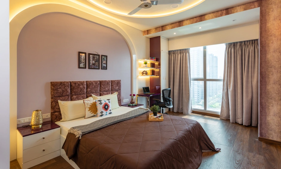 Arched wall accent and integrated study unit in a modern Mumbai bedroom with wood flooring.
