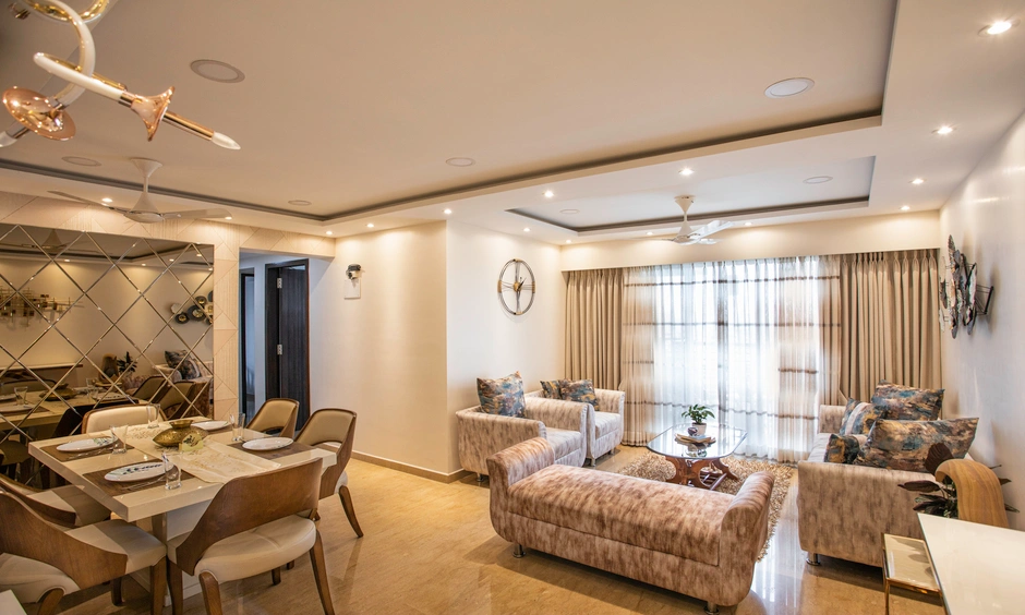 Bright 2 BHK living room in Powai Mumbai with layered ceiling lights and neutral seating.