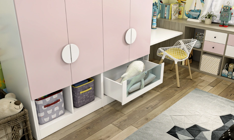 Close-up of pink bedroom wardrobe with open lower cubbies and a transparent pull-out drawer holding toys.