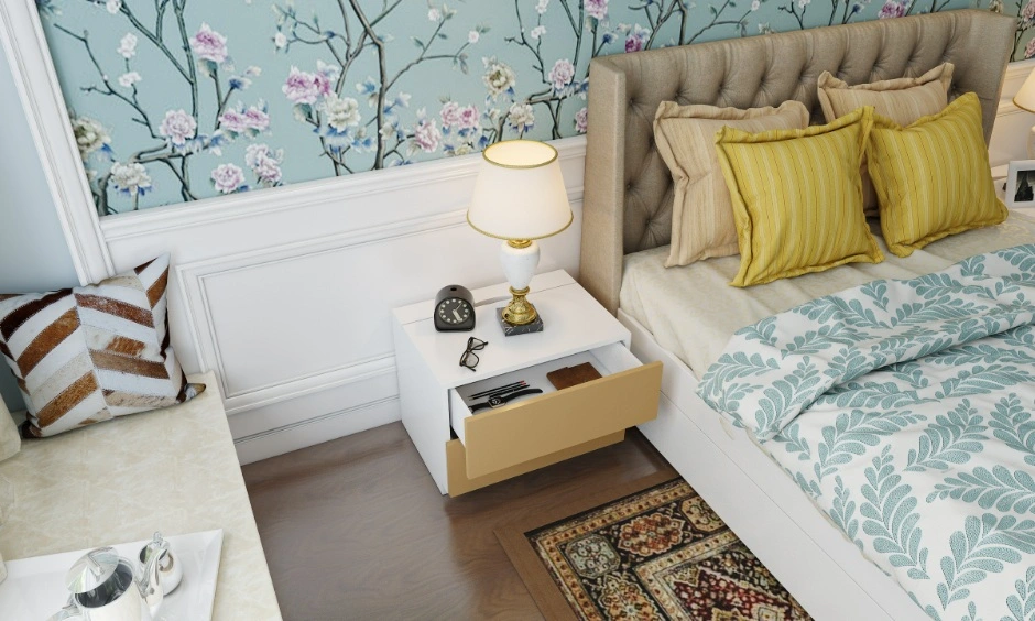 Cozy bedroom design featuring floral wallpaper, a bedside table drawer, and soft furnishings
