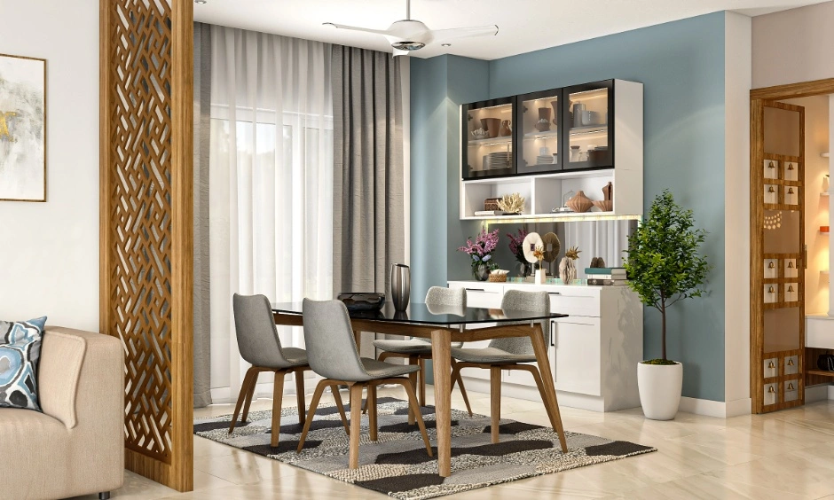 A dining rug and wooden jaali partition establishing functional zones within an L-shaped room.