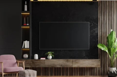 Modern floating TV unit on a black textured wall with slatted panelling and concealed storage.