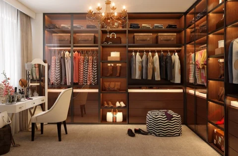 Glass-fronted timber walk-in wardrobe with a vanity and chandelier showcases a premium luxury wardrobe design.