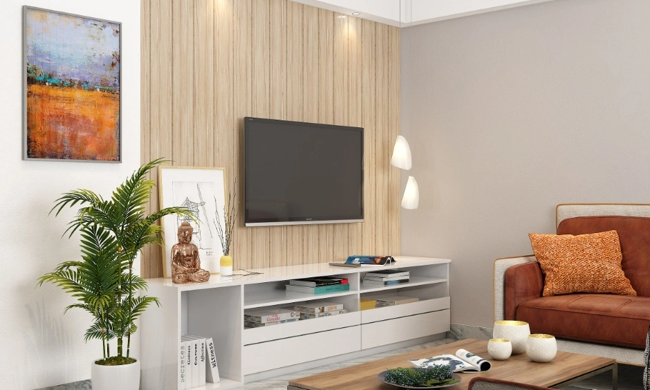 Living room design in Noida with TV unit, wooden wall panel, indoor plant, wall art, pendant lights and sofa seating.