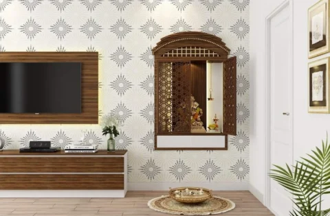 Wall-mounted wooden mandir featured in a pooja room layout with intricate white CNC jaali back panelling.