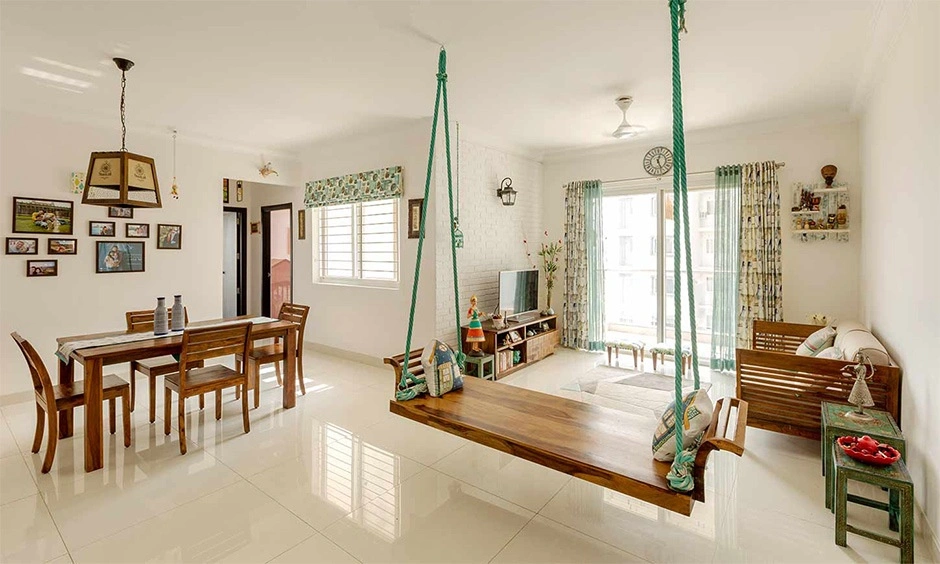 A bright living room features an elegant wooden swing and off-white ceramic tiled floor.