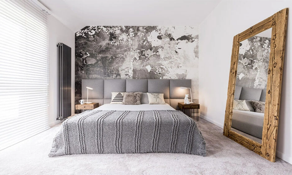 A full-height mirror reflects daylight into a compact bedroom with neutral furnishings.