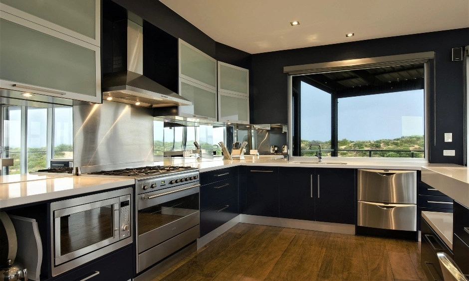 A dark kitchen uses glossy black cabinetry with reflective surfaces and integrated lighting.