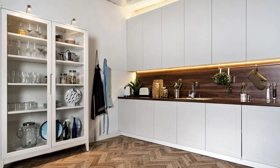 White shutters and a walnut-look backsplash over herringbone flooring show handleless door styles and finishes.